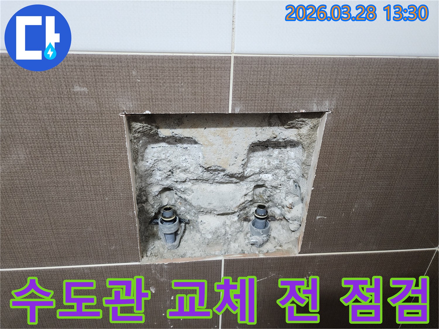 중랑구 상봉동 화장실의 수도관 교체 전-벽면 타일을 제거하고 내부 매립 배관의 상태를 점검하는-공사 현장의 한 장면입니다.