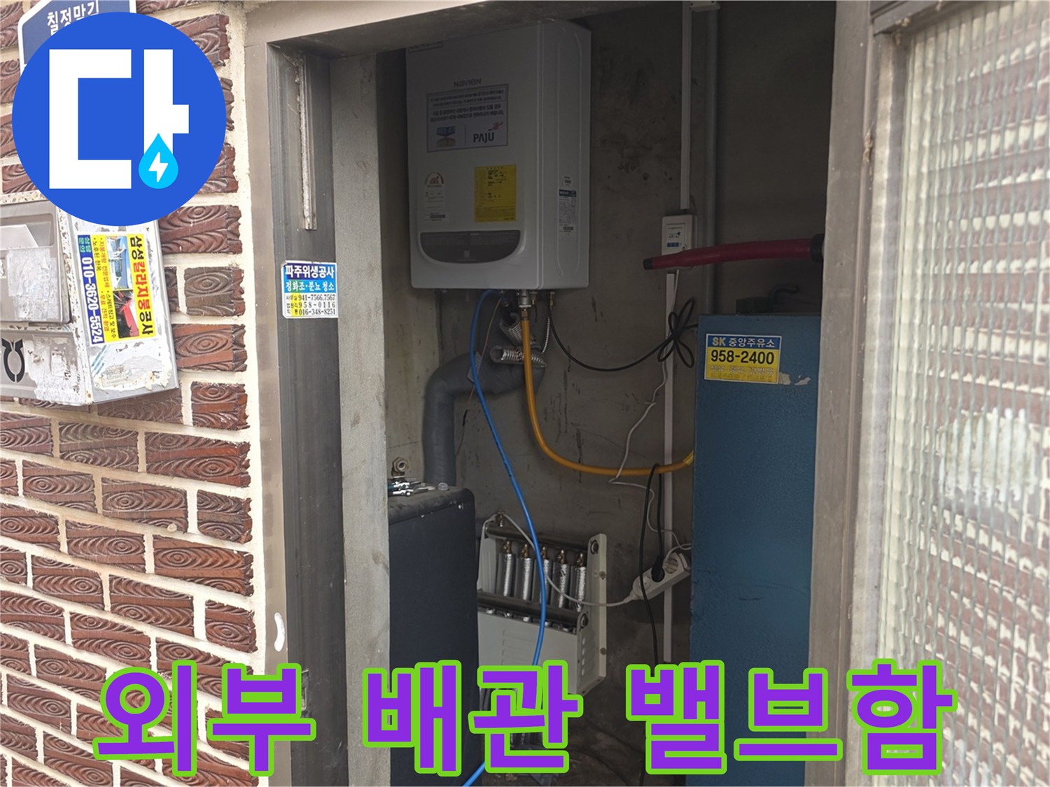 건물 외벽 벽돌 사이에 위치한 배관 제어 장치와 전기 함체