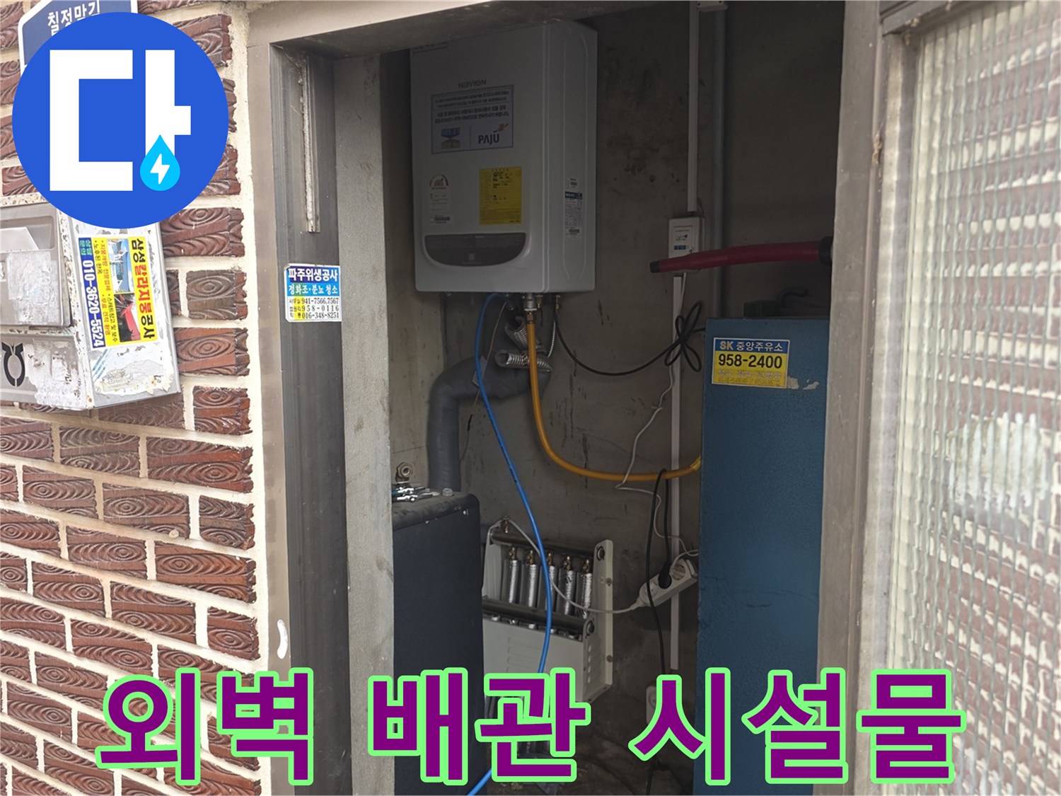 벽돌 외벽에 부착된 수도 관련 장치와 전기 분전반의 상세 모습