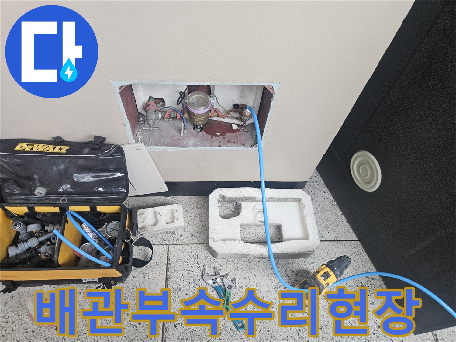 벽면 굴착 부위의 수도 배관과 작업용 공구 배치 모습