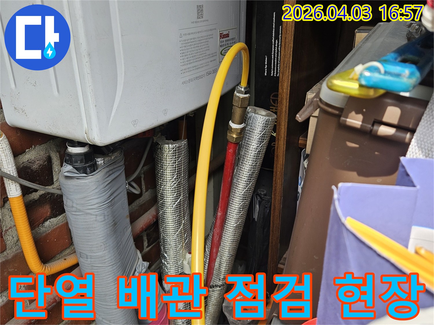 오래된 주택의 보일러실에서 발견된 다양한 배관들의 모습입니다-특히 가스관과 온수관의 접합부를 중점적으로 살펴보고 있습니다.