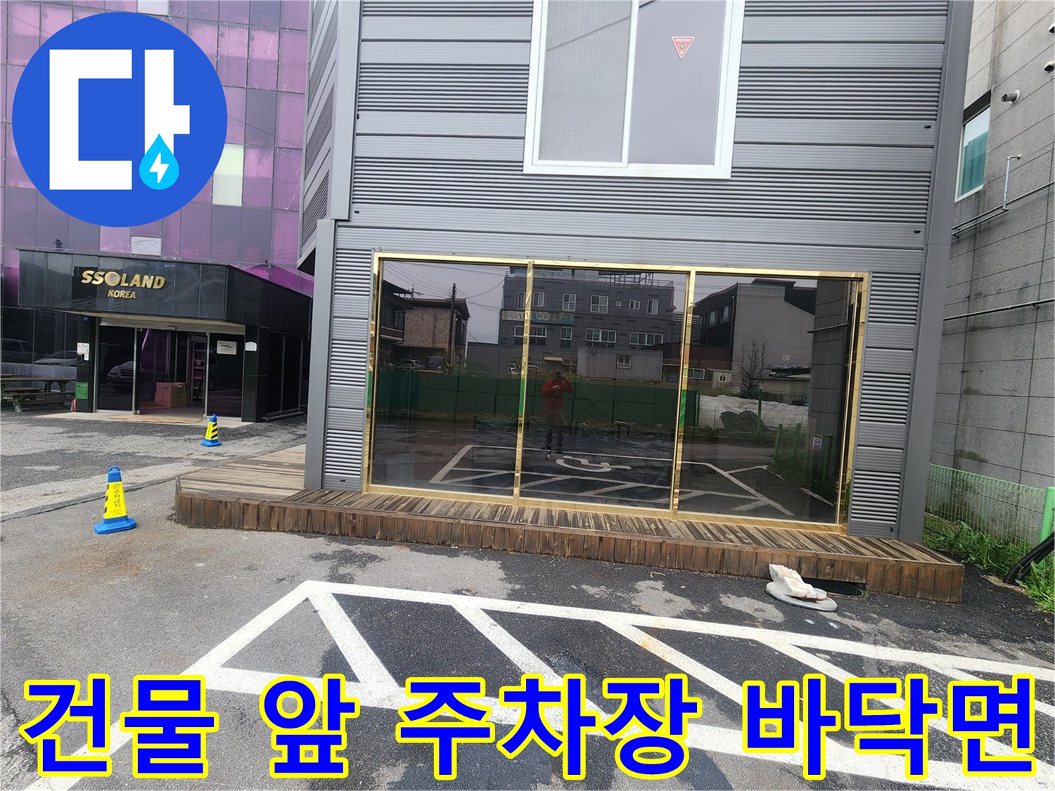상가 건물 입구 근처의 침하된 아스팔트 주차장 지면