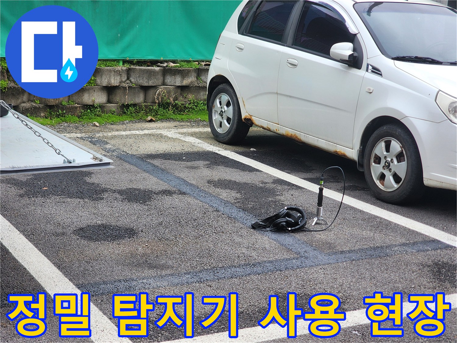 주차장 바닥의 어두운 습기 자국과 배관 진단 장비의 배치 상황