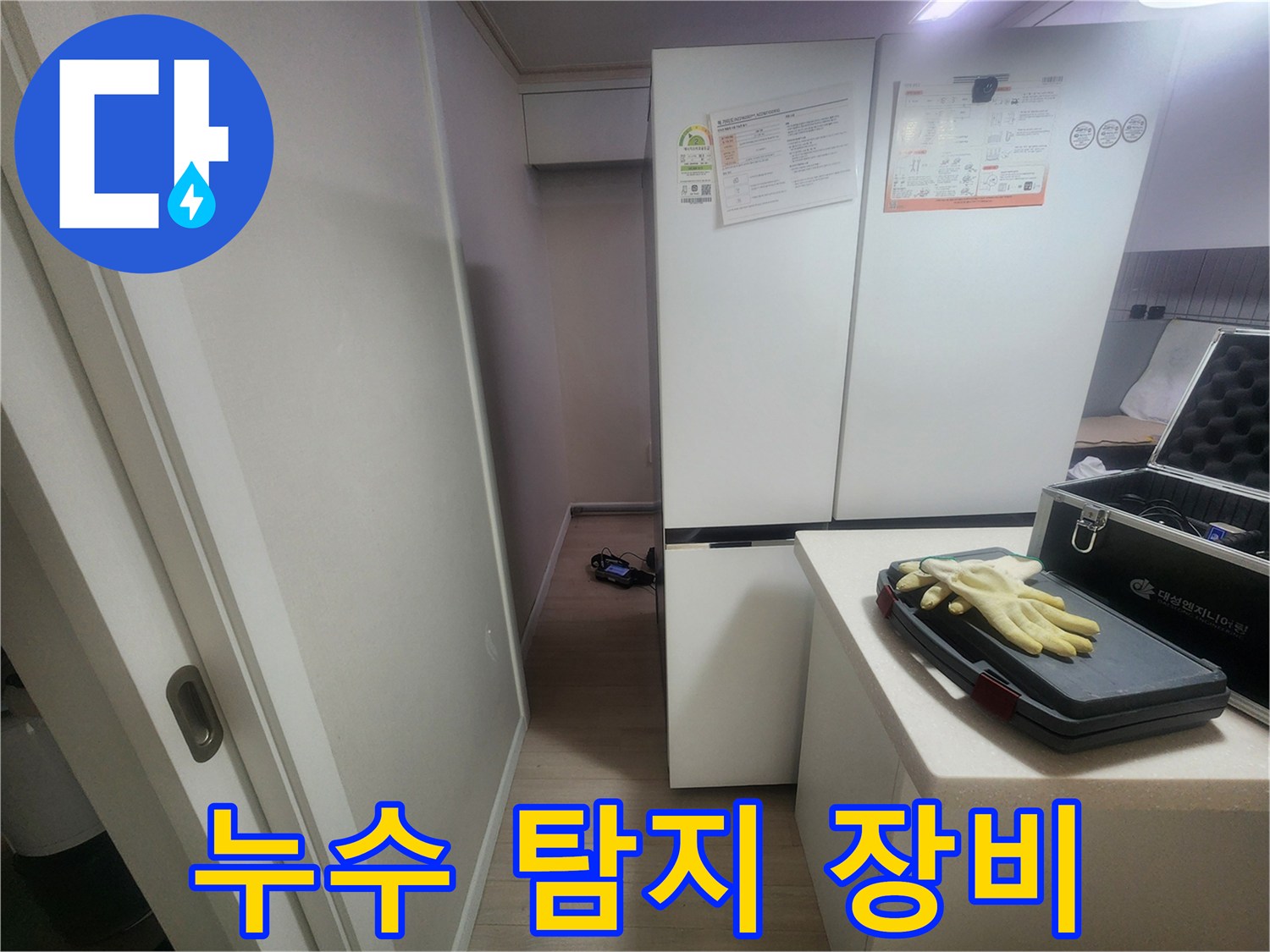 작업용 장갑이 놓인 누수 진단용 가방과 냉장고 옆 공간