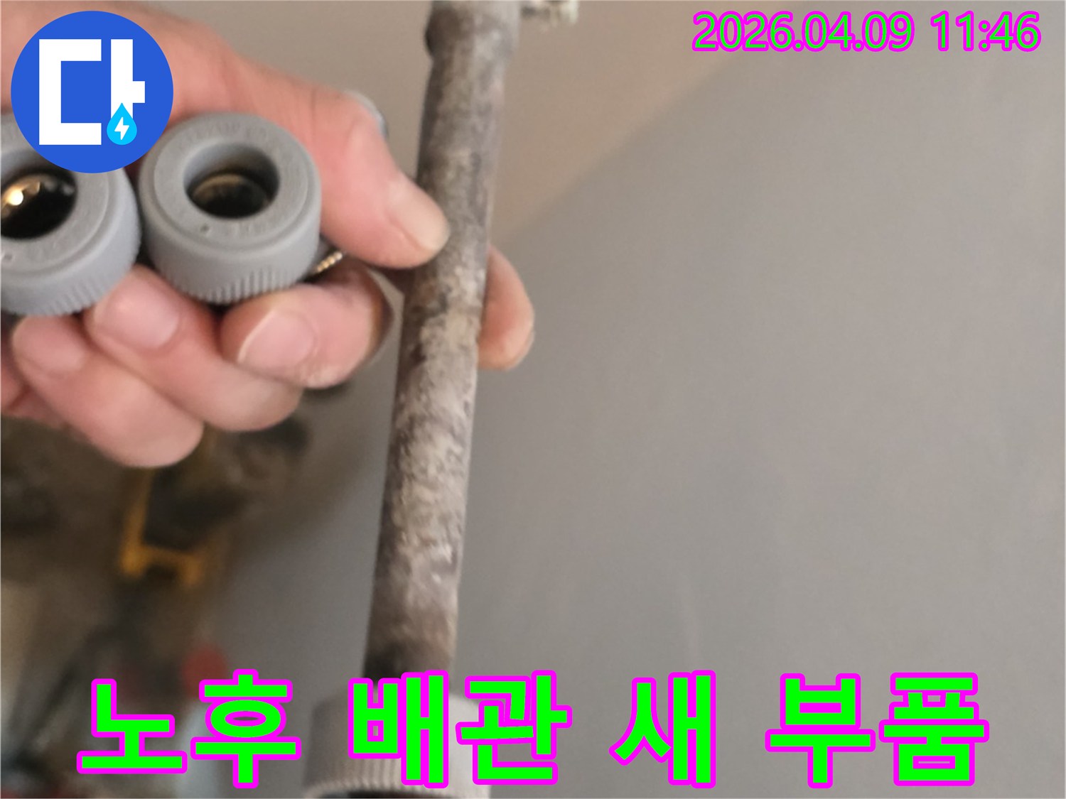 이 사진은-오랜 사용으로 노후된 수도관과-새롭게 교체할 배관 부품을-함께 보여주고 있습니다