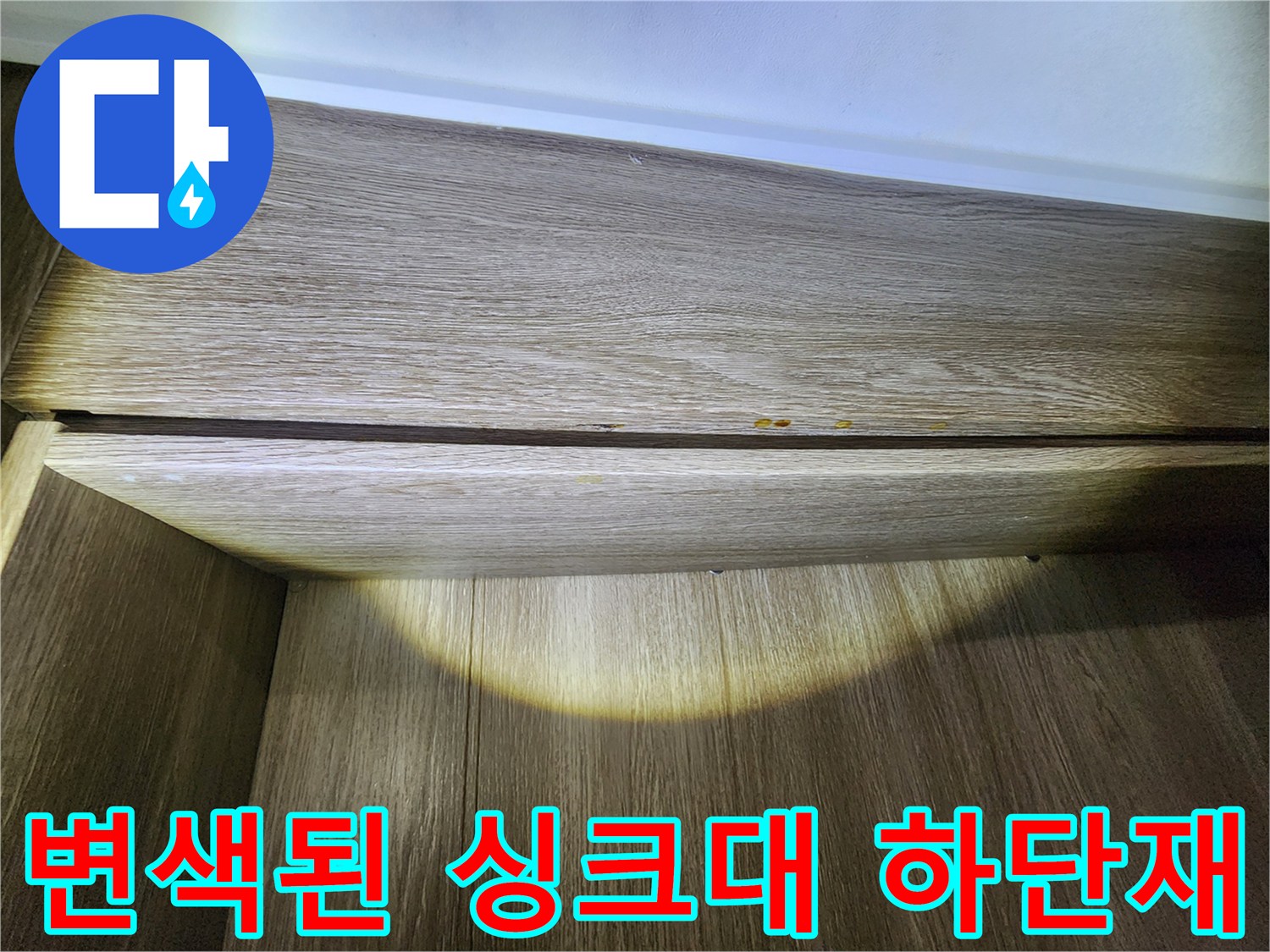 싱크대 밑 나무 마감재에 나타난 누수 흔적과 변색 부위