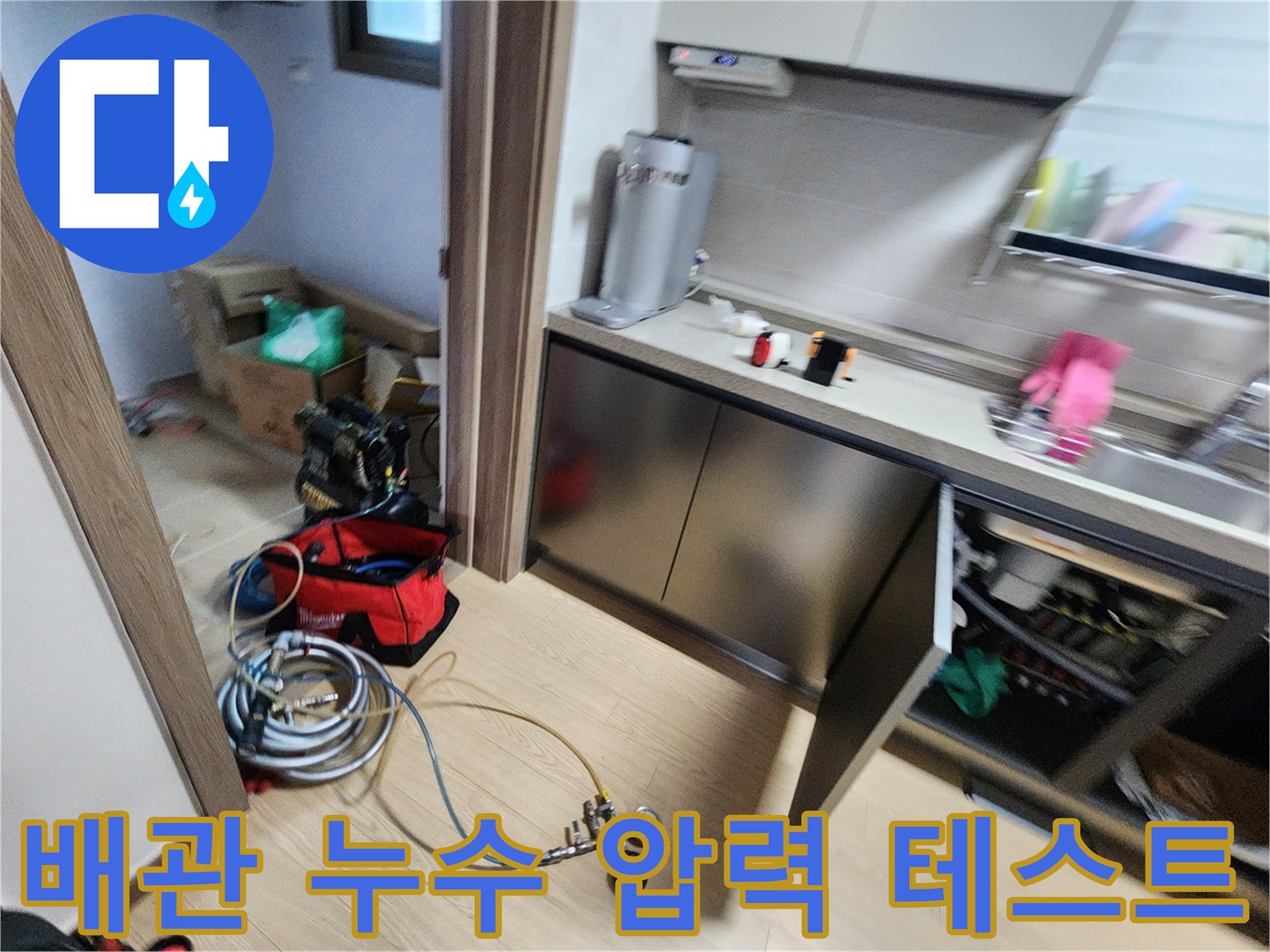 싱크대 하부 바닥에 놓인 압력계와 배관 연결용 호스 뭉치