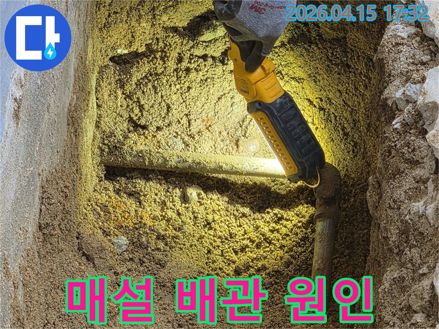 전문가가-손전등으로-땅속에-묻힌-매설-배관의-누수-원인을-정밀하게-분석하고-있는-모습입니다.