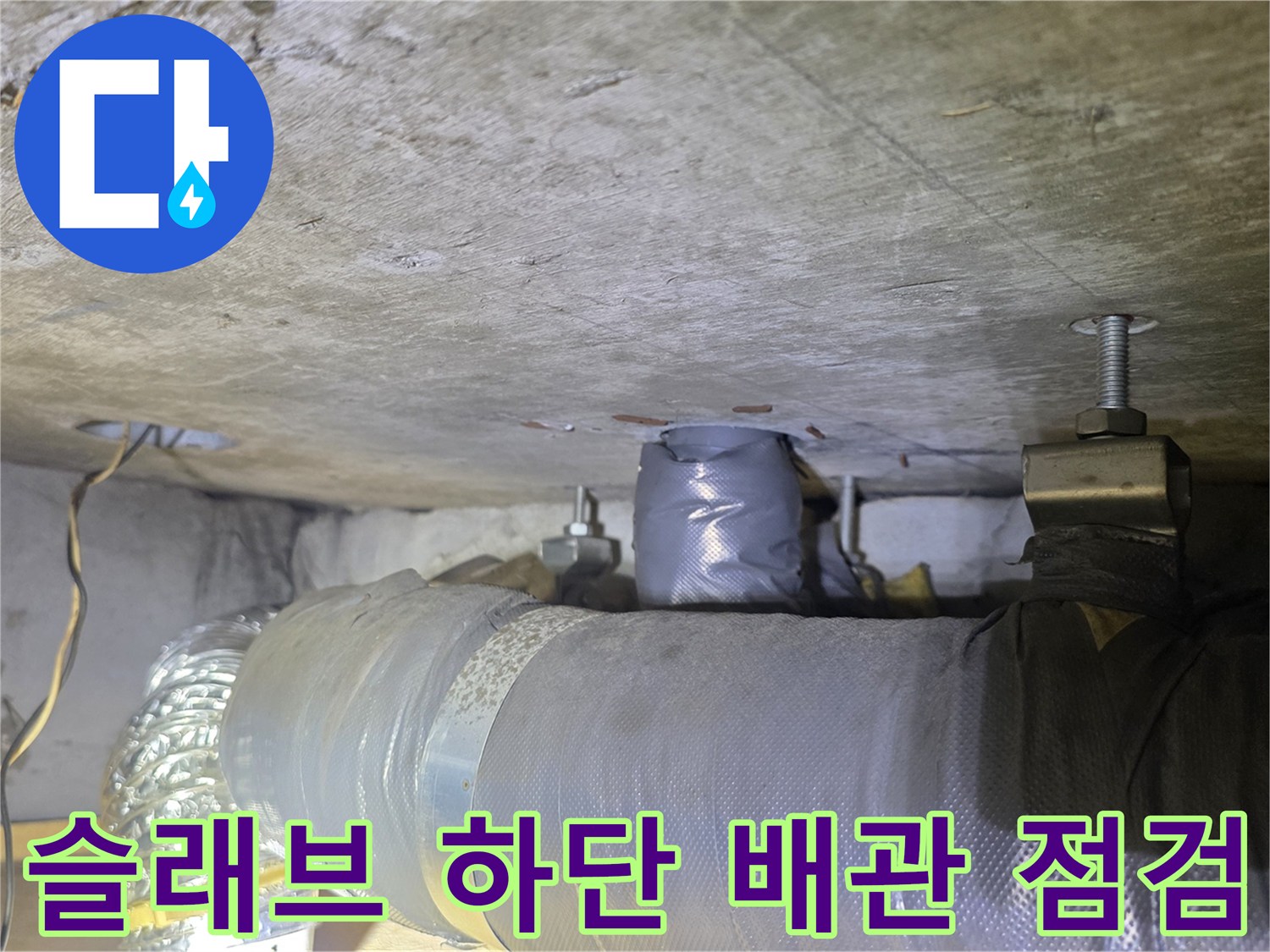 콘크리트 천장 아래 설치된 은박 보온재 씌워진 배관의 모습