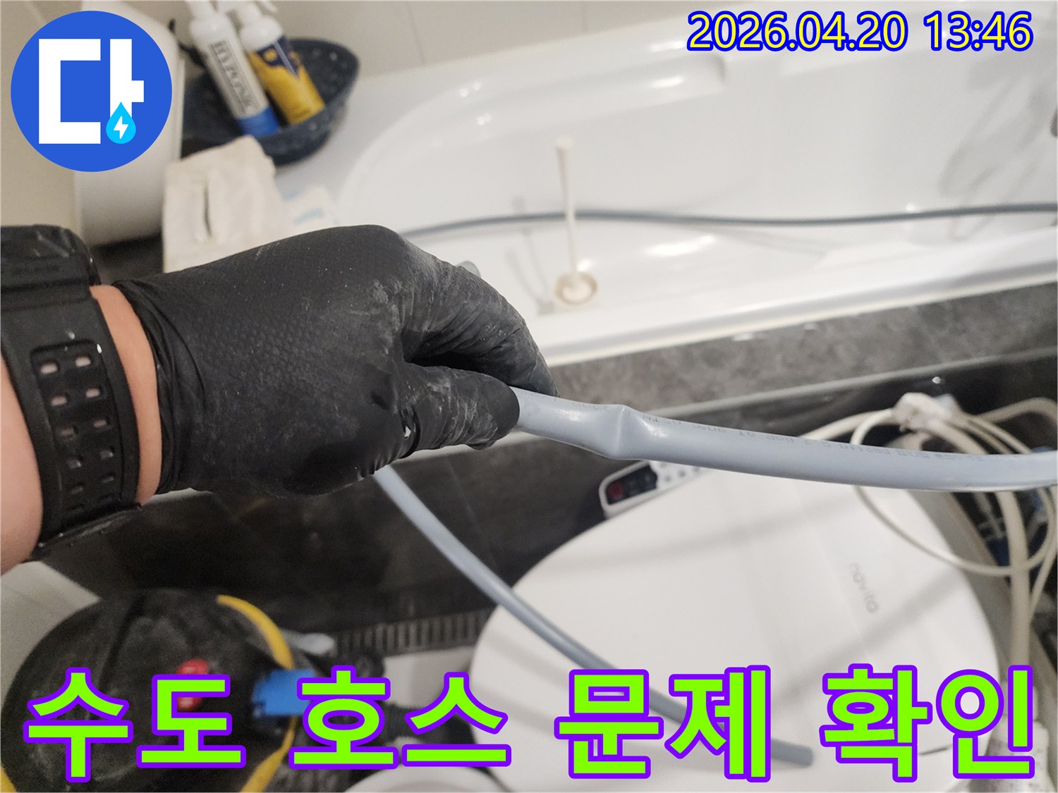 누수 전문 엔지니어가 검은 장갑을 끼고-욕실 수도 호스의 꺾임이나-손상 여부를 주의 깊게 점검하고 있습니다.