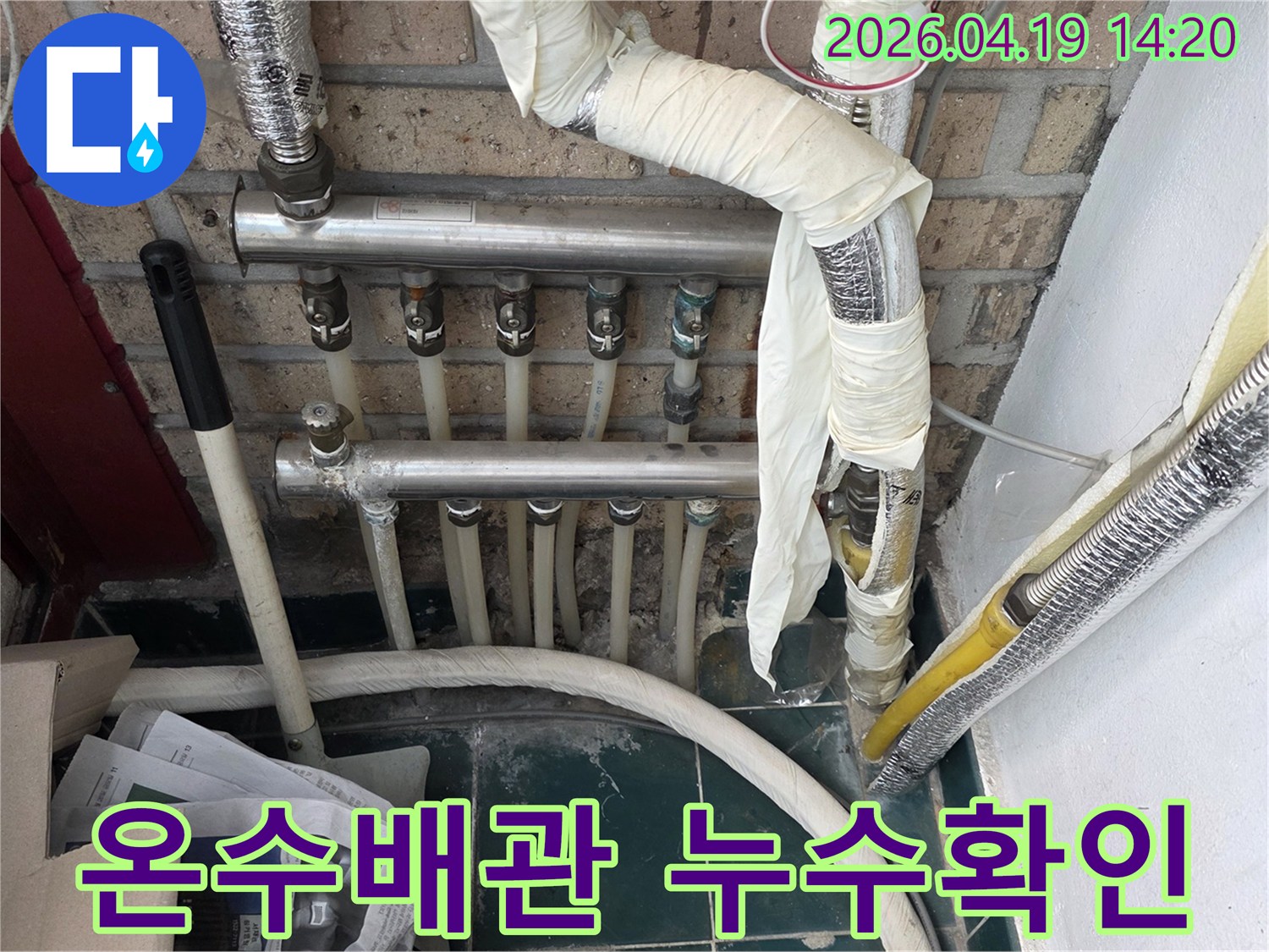 오래된 아파트의 온수 배관과 분배기 주변에서 누수 여부를 확인하는 전문적인 점검 현장