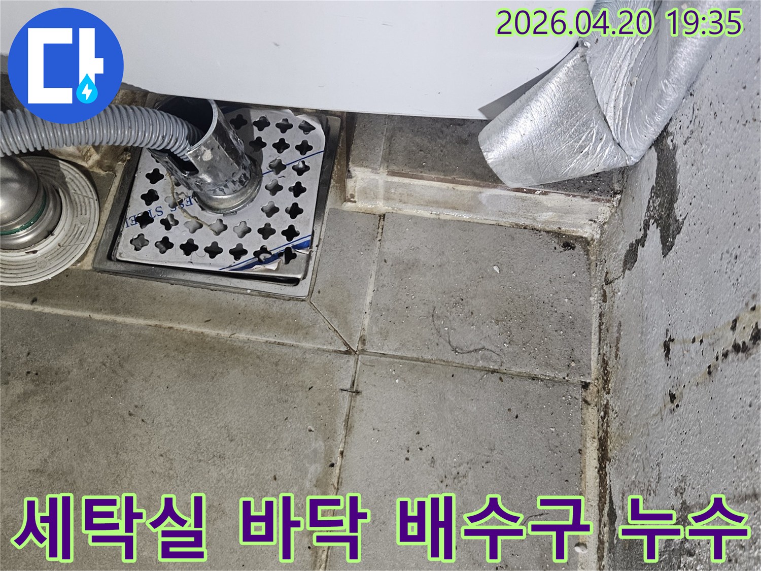 세탁실 바닥 배수구와-세탁기 호스가-연결된 모습으로-주변에 물때와-오염이 보이는-누수 현장입니다.