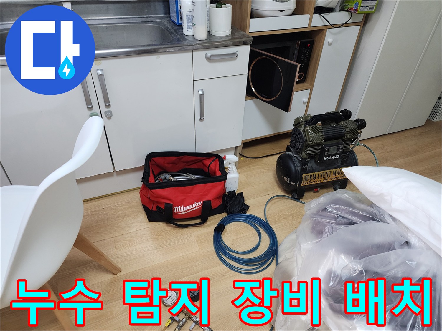 싱크대 아래 작업 공간에 놓인 압력계와 공구 세트