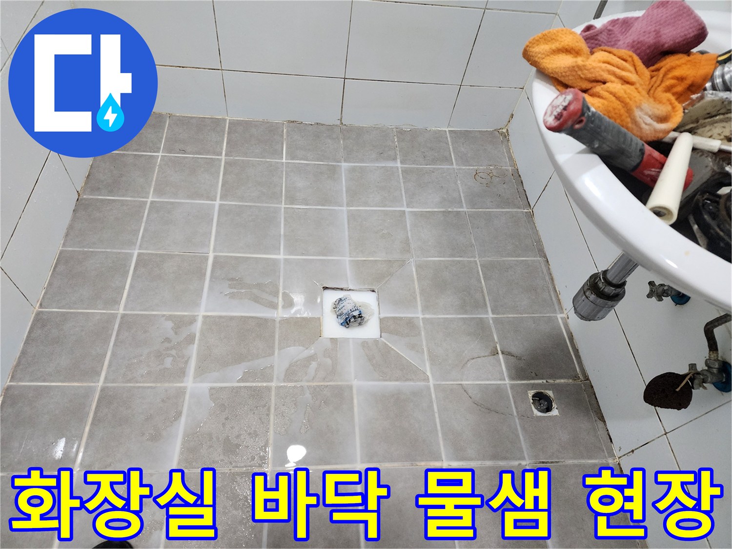 화장실 바닥 타일 위에 물이 고여-누수가 진행 중임을-보여주는 현장 사진입니다