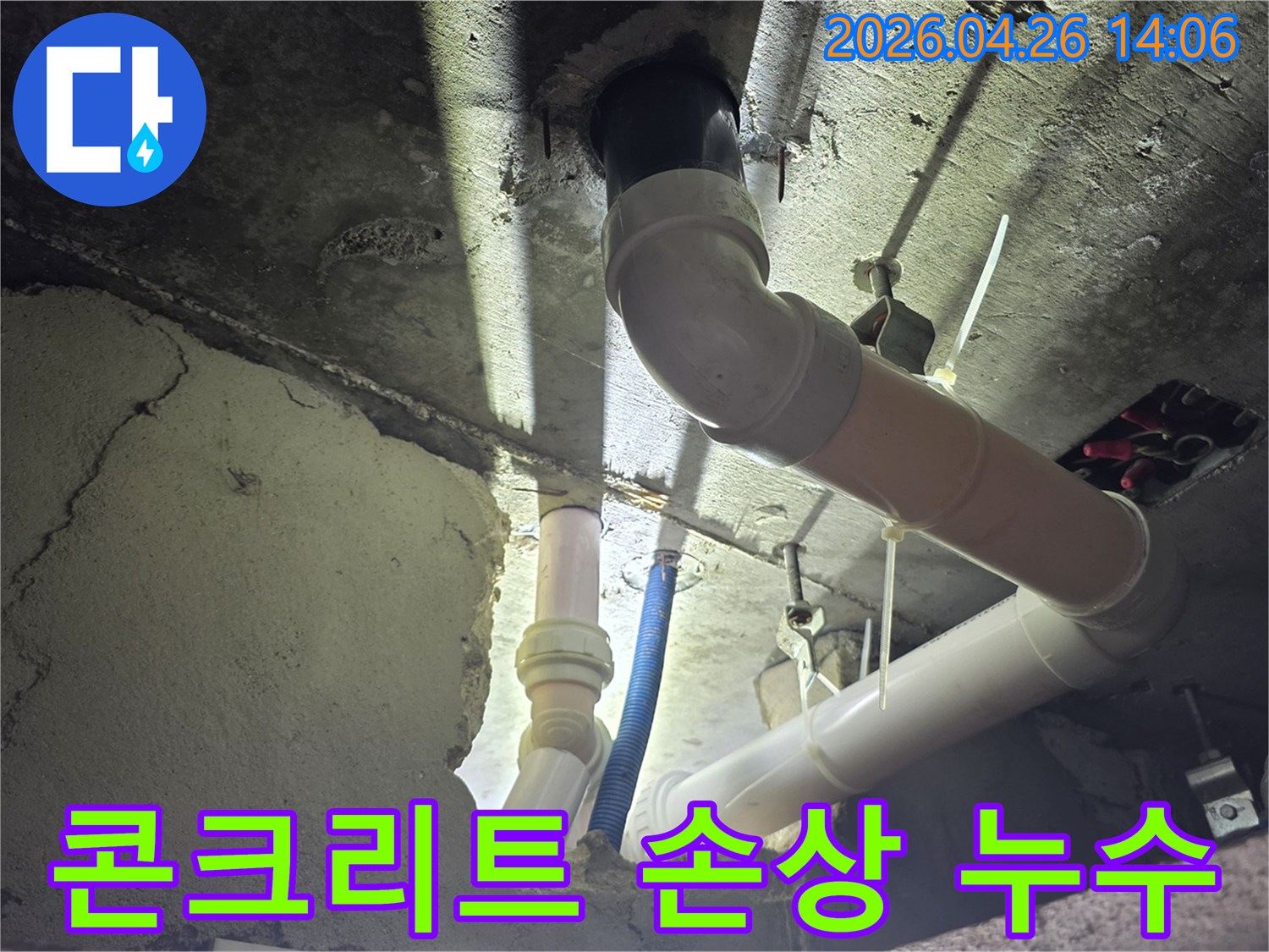 이 이미지는 아파트 천장 배관 주변의-콘크리트가 누수로 인해 손상된-현장을 보여주며-누수 탐지 작업의 필요성을 강조합니다.