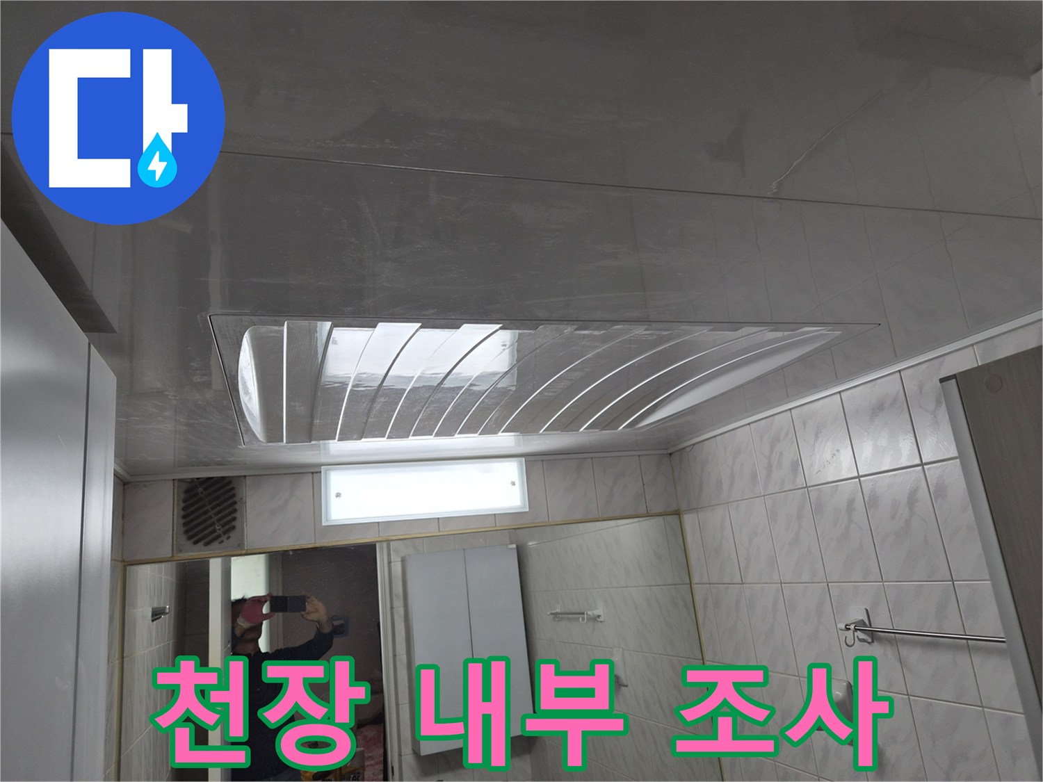 화장실 천장 점검구를 통해 상부 배관의 상태를 관찰하고 있습니다.