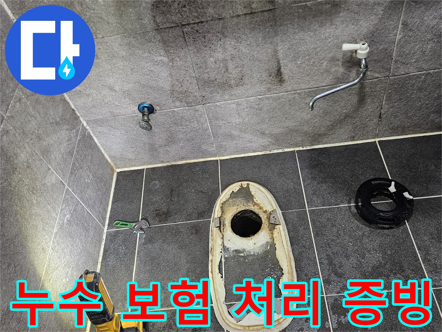 변기가 제거된 욕실 바닥의 배수구와-주변 타일에 스며든 물의 흔적을-손전등으로 밝혀 누수 보험 처리를 위한 증빙 자료를 확보하는 모습입니다.