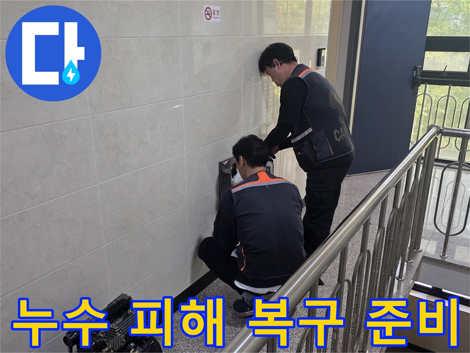 두 명의 전문 기술자가 건물 벽면의 누수 의심 지점을 정밀하게 탐지하며 누수 피해 복구를 위한 준비를 하고 있습니다-고객의 불편을 최소화하기 위한 노력입니다.
