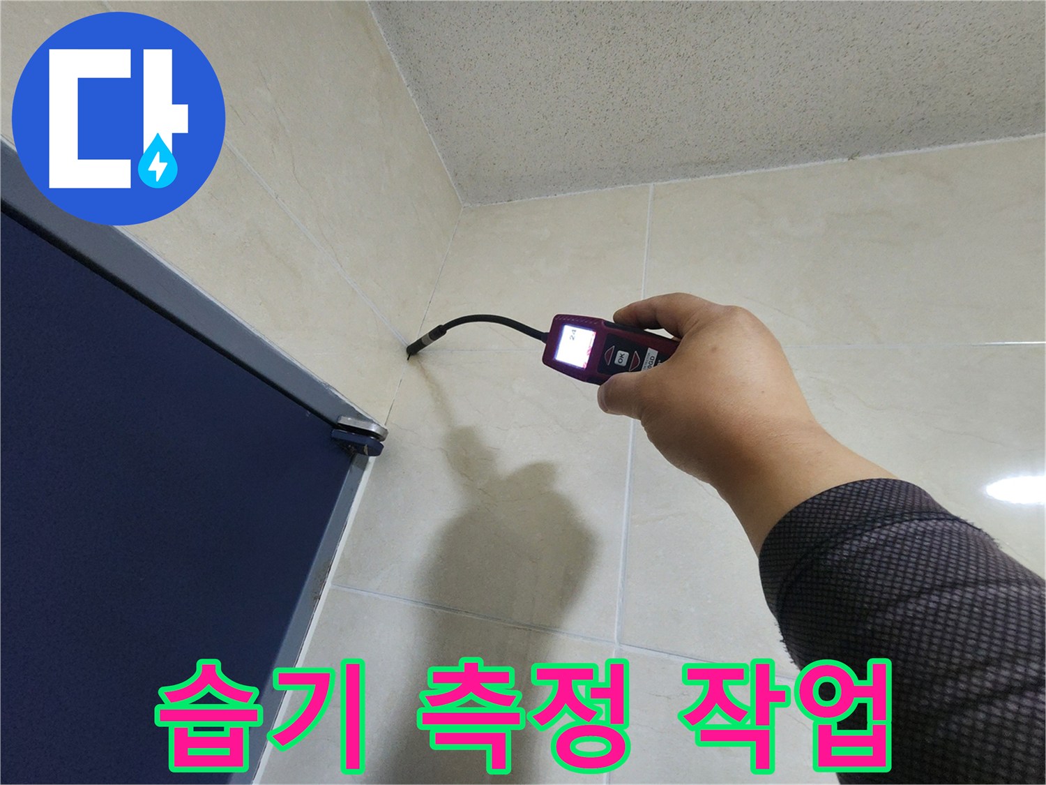 전문 누수 엔지니어가-타일 벽면 모서리의-숨겨진 습기를-정밀하게 측정하여-누수 여부를 확인하고 있습니다.