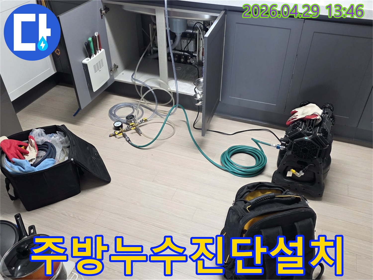 동안구 아파트 주방 싱크대 하부에서-누수 진단을 위한-압력 게이지와 호스-그리고 공기 압축 장비를-설치하는 작업이 진행 중입니다