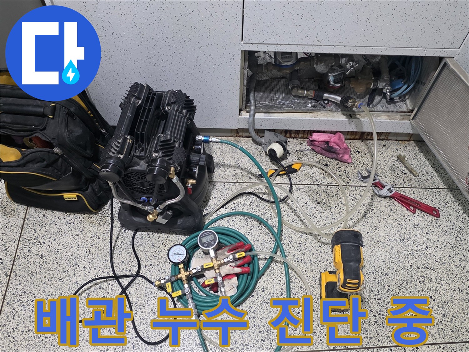 싱크대 하부 점검구에 연결된 디지털 압력계와 공압 테스트용 호스들