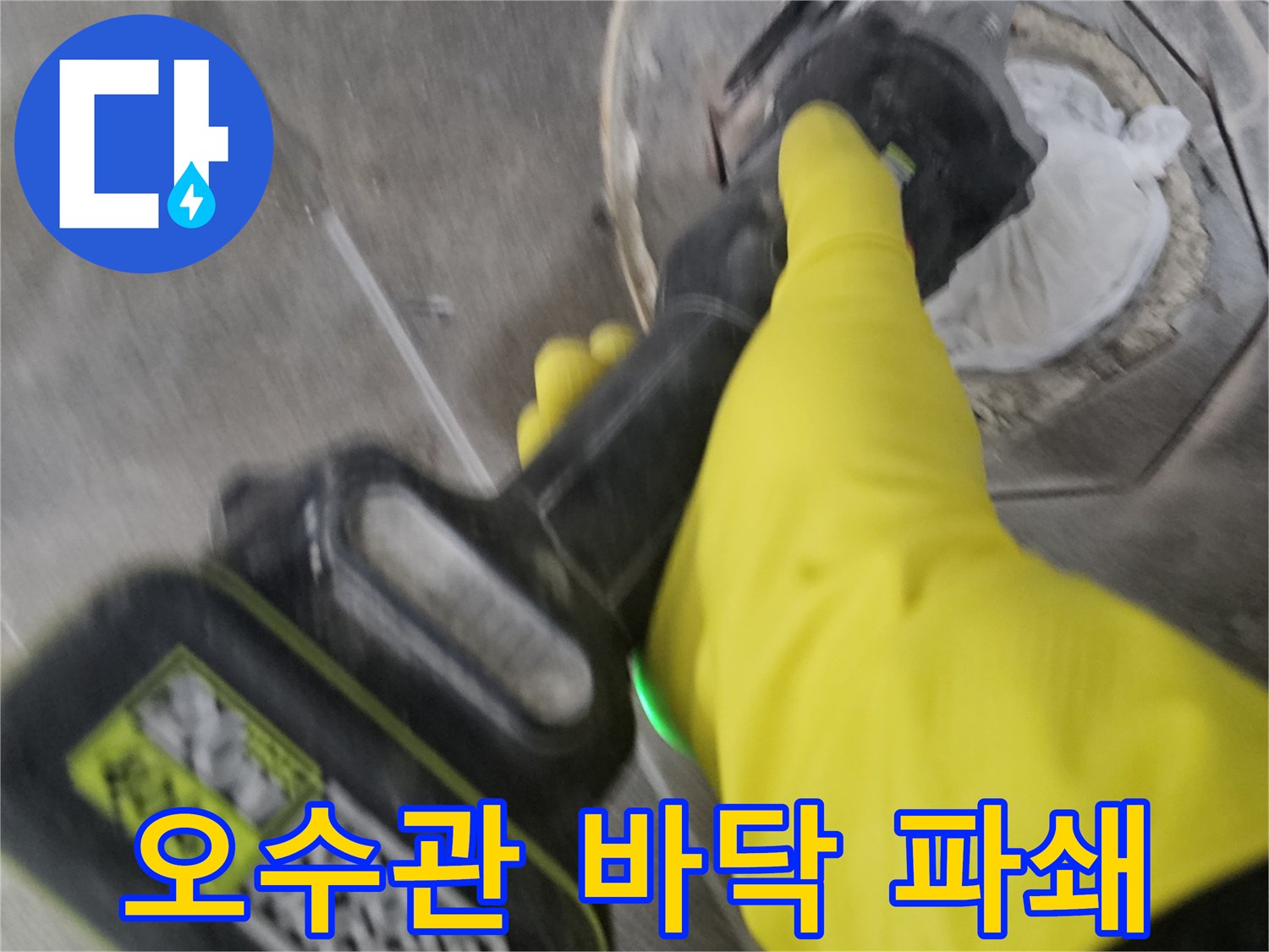 노란 장갑을 낀 작업자가-전동 커터로-오수관 주변의 바닥 타일을-정확하게 잘라내어-파쇄하는 모습입니다.