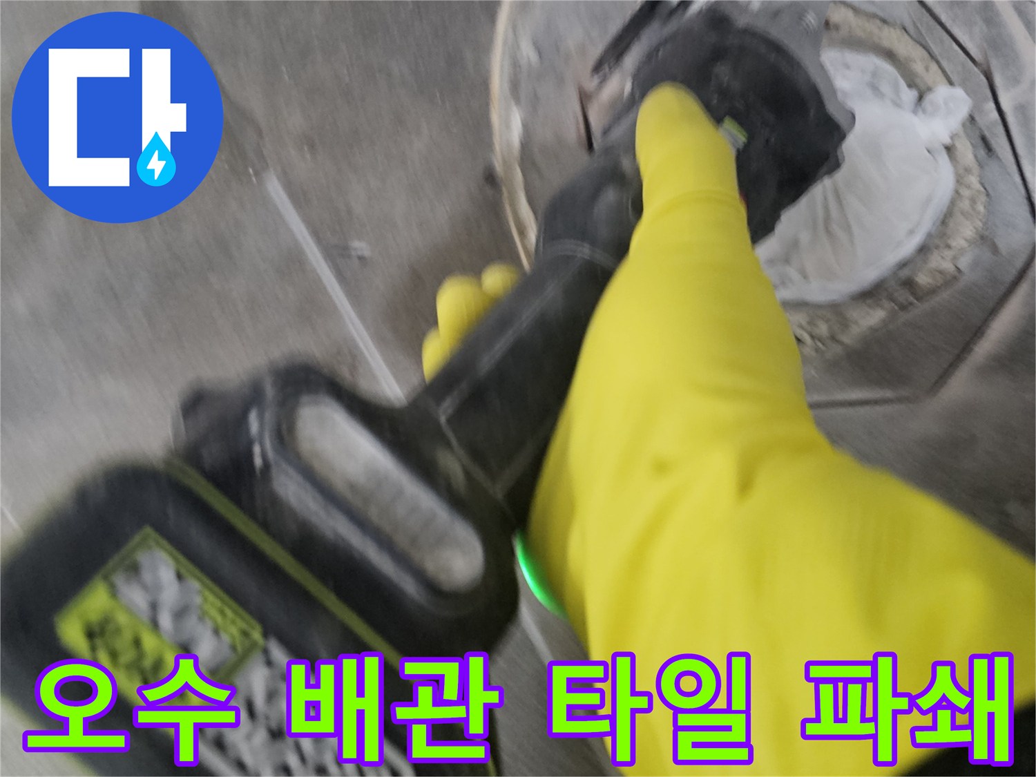 노란색 보호 장갑을 착용한-작업자가-전동 공구를 이용해-오수 배관 주변의-굳은 타일을-조심스럽게 파쇄하는 모습입니다.