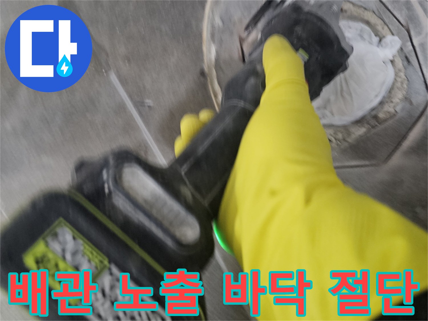 노란색 안전 장갑을 착용한-기술자가-전동 공구를 사용하여-배관 주변의 바닥 타일을-정교하게 절단하여-배관을 노출시키는 현장입니다.