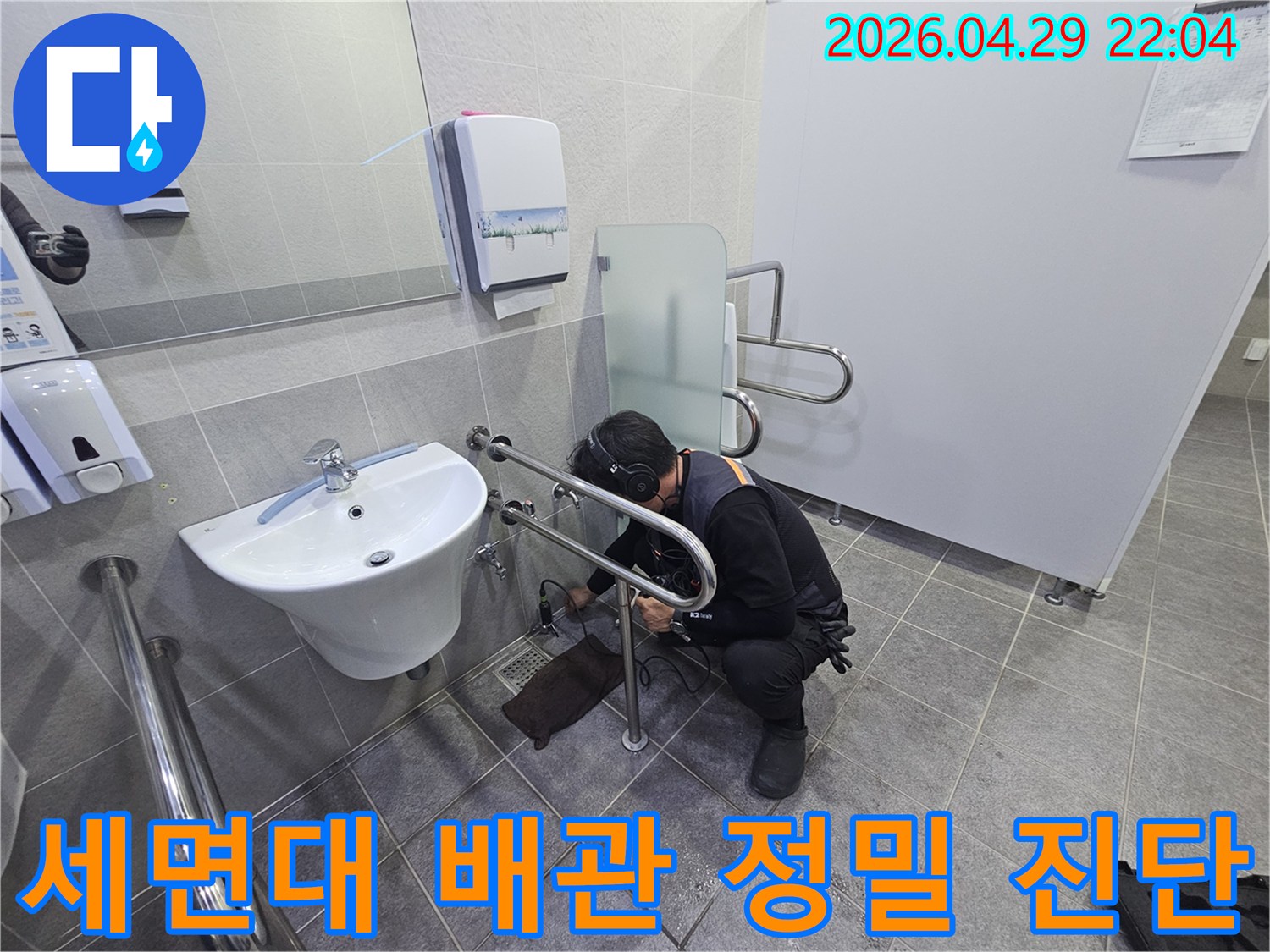 누수 전문가가-청음식 탐지기로-화장실 세면대 하부 배관에서-누수음을 정밀하게 듣고-원인을 파악하는 중