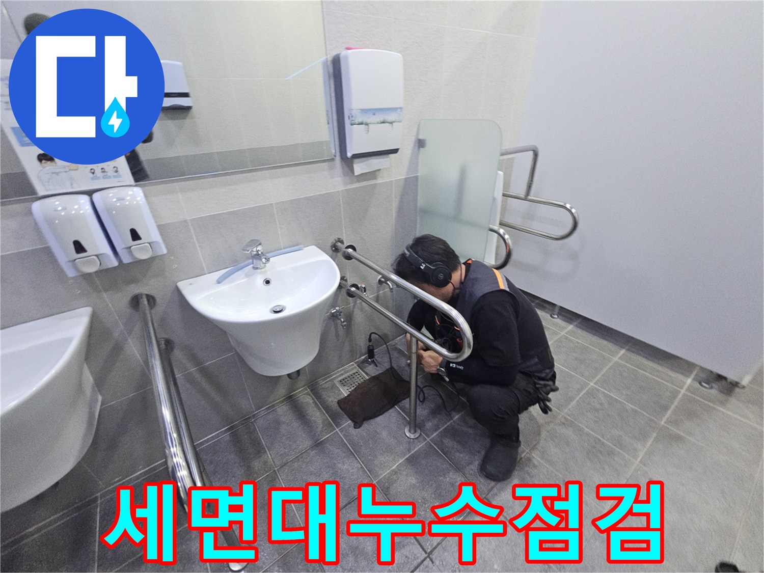 헤드폰을 착용한 기술자가-공용 화장실의 세면대 배관에서-미세한 누수 지점을 찾아내고 있습니다.