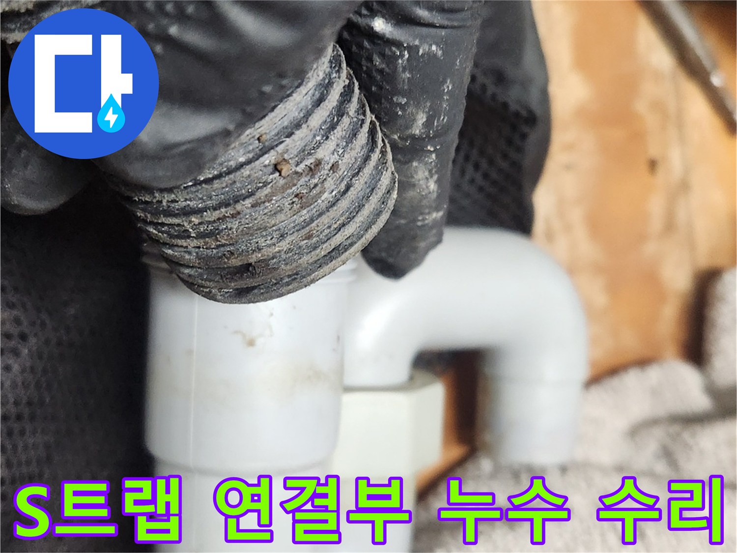 검은 장갑을 낀 손이-누수가 발생한 S트랩의 연결 부위를-정밀하게 분리하여 점검하고 있습니다