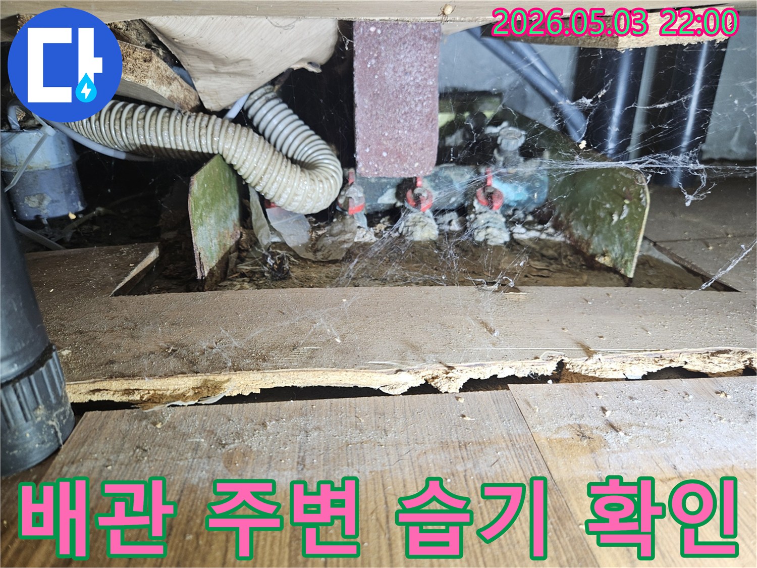 아파트 바닥 아래-배관 주변에 고인 물과-습기로 인한 손상을 보여주는-누수 현장 사진입니다