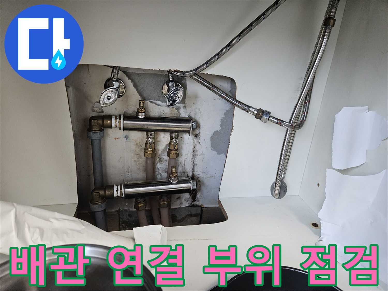 벽면에 고정된 은색 배관과 수전 호스 연결부