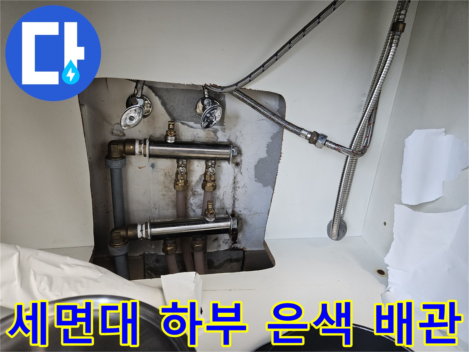 세면대 아래에 노출된 은색 수도 호스와 연결 부속들