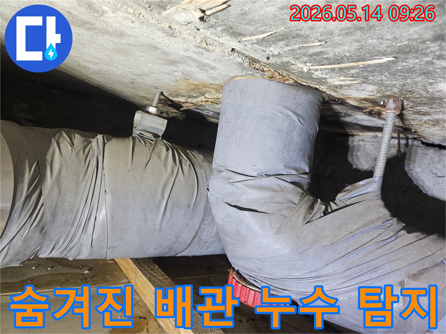 천장 아래 설치된 배관에서 물이 새어-단열재가 젖어있는-숨겨진 누수 현장을 보여줍니다