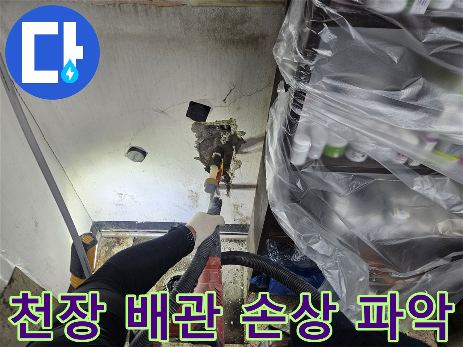 누수 원인을 찾기 위해-손상된 천장과 노출된 배관의 문제점을-전문가가 면밀히 확인하고 있습니다