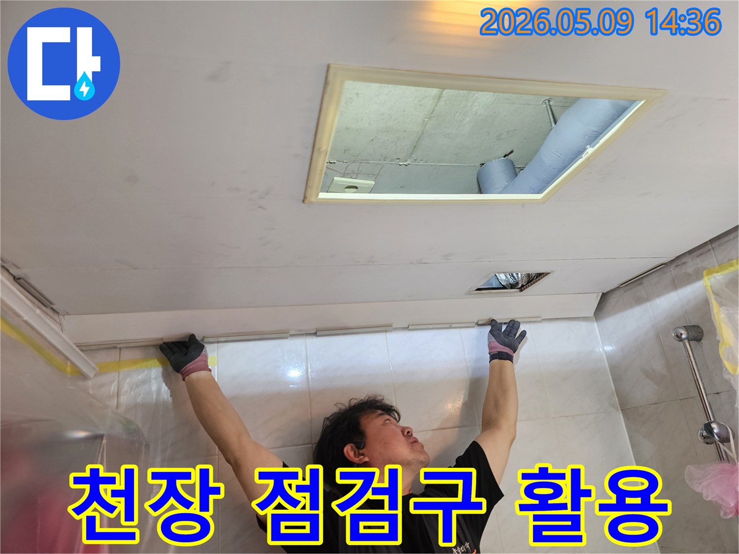 누수 엔지니어가 천장 점검구를 열고-내부 구조와 배관을-세밀하게 관찰하는-모습입니다.