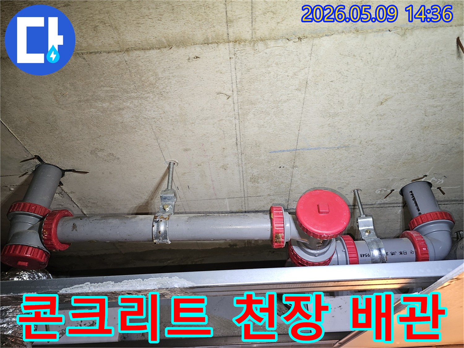 콘크리트 천장에 고정된 회색 배관과-붉은색 캡이 달린 부속품-누수 여부를 확인하기 위한 현장 점검