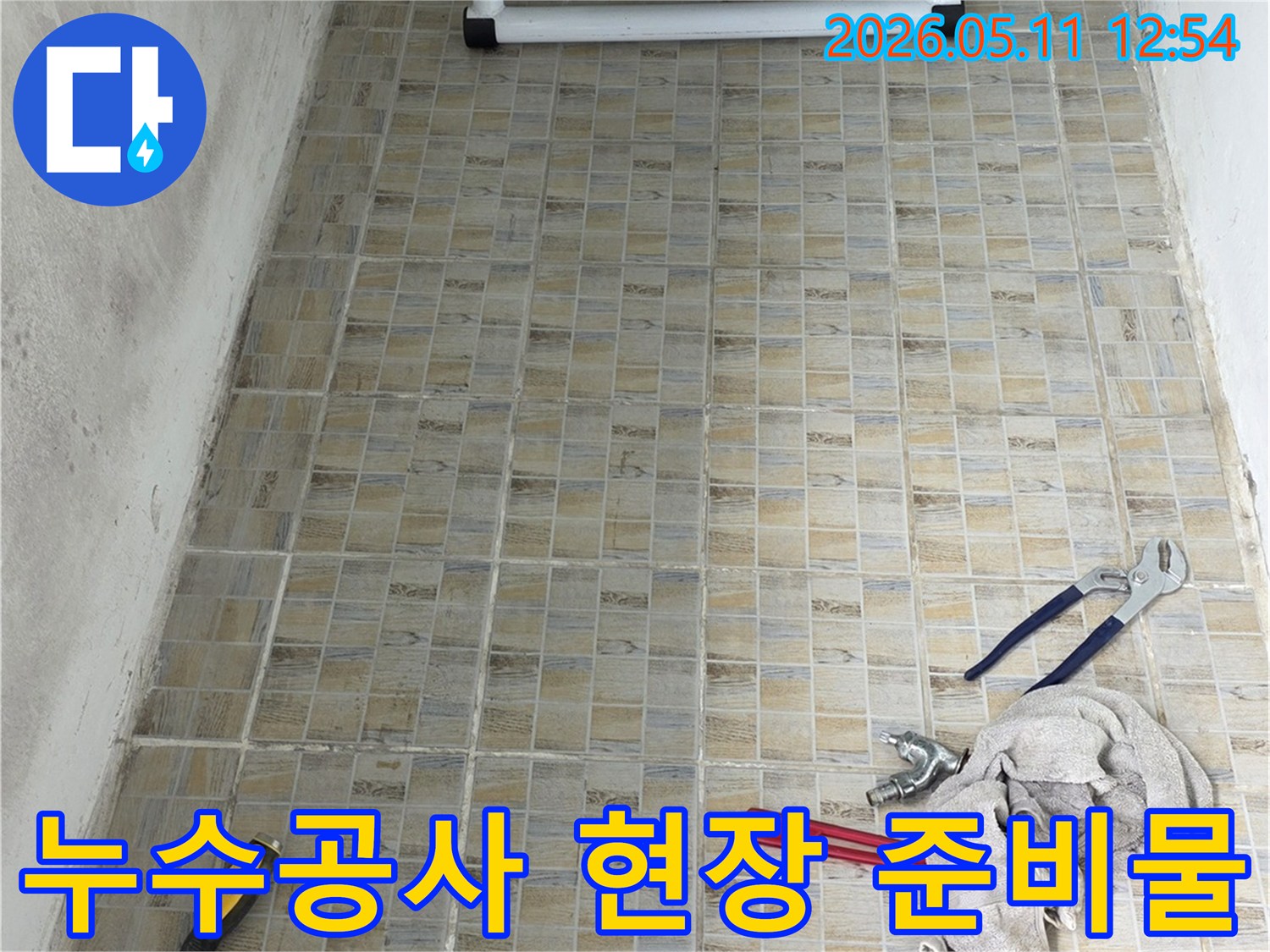 누수 공사 현장에서-타일 벽면을 배경으로-작업 도구들이 가지런히 놓여있는 모습