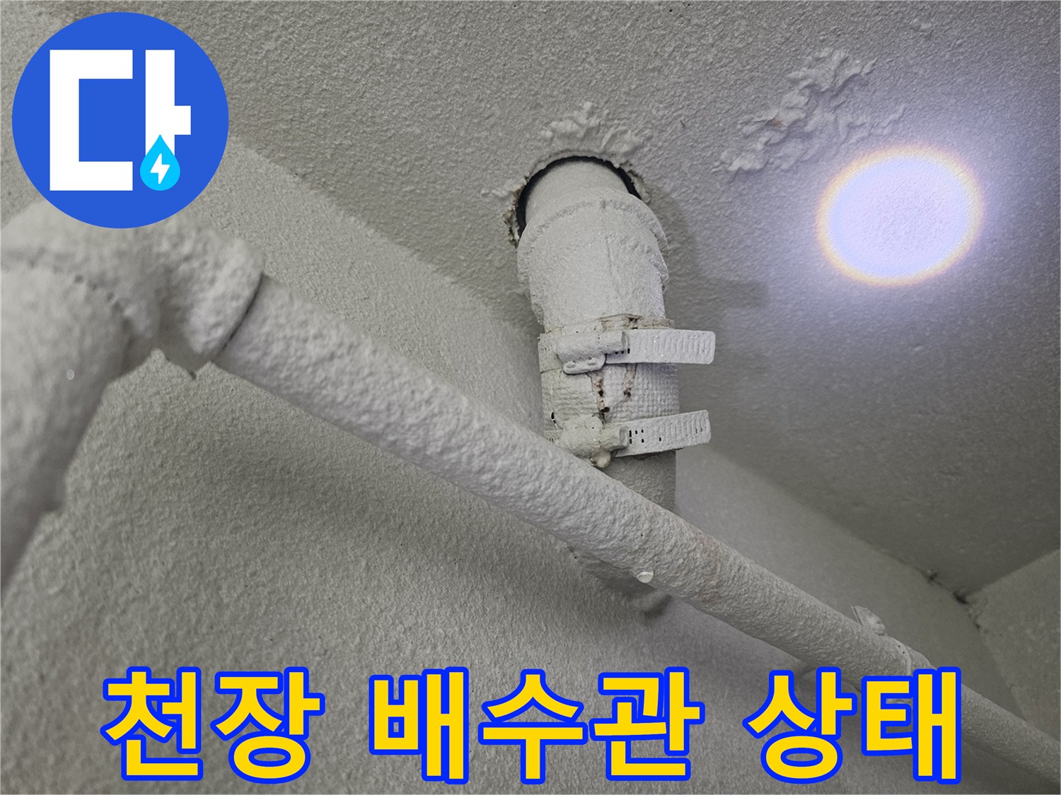천장에 설치된 흰색 배수 파이프와 고정 클램프 사진입니다.