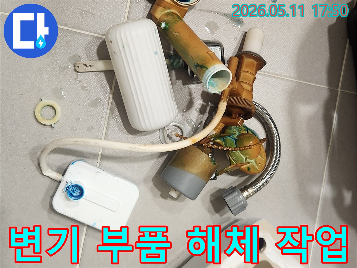 안방 변기에서 발견된 누수 문제로 인해-낡고 부식된 변기 부속들이 해체되어 바닥에 놓여 있습니다-새 부품으로 교체하여 문제를 해결할 준비가 완료되었습니다