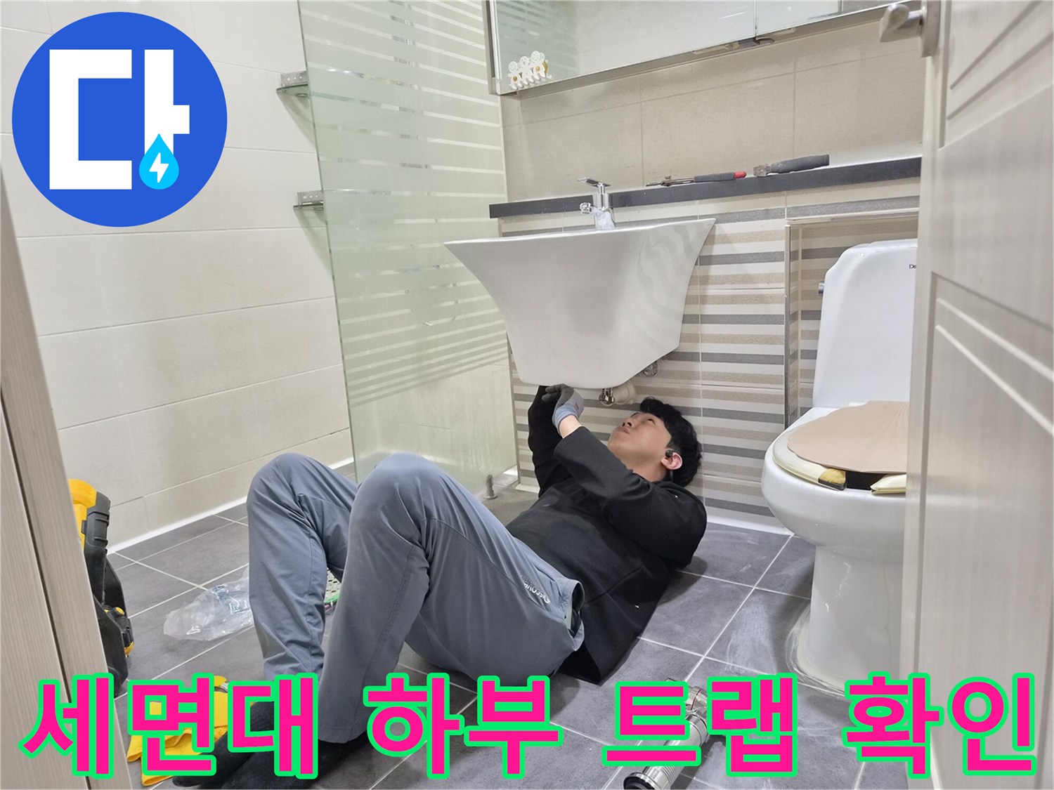 세면대 아래쪽 배관 연결 부위의 물샘 여부를 점검하는 작업 장면