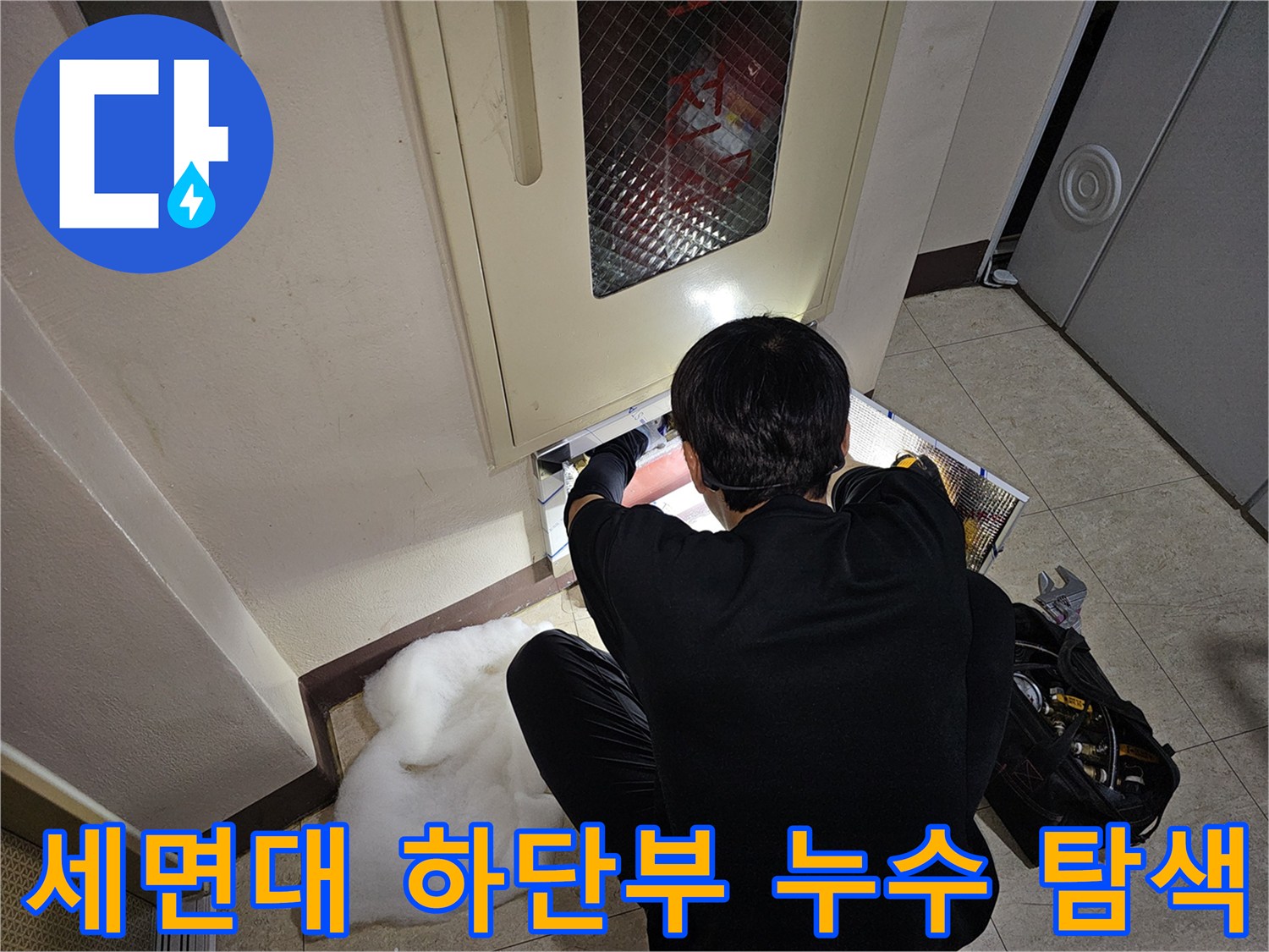 좁은 세면대 아래 공간에서 엔지니어가 배관의 연결 상태를 꼼<0xAE>꼼히 점검합니다.