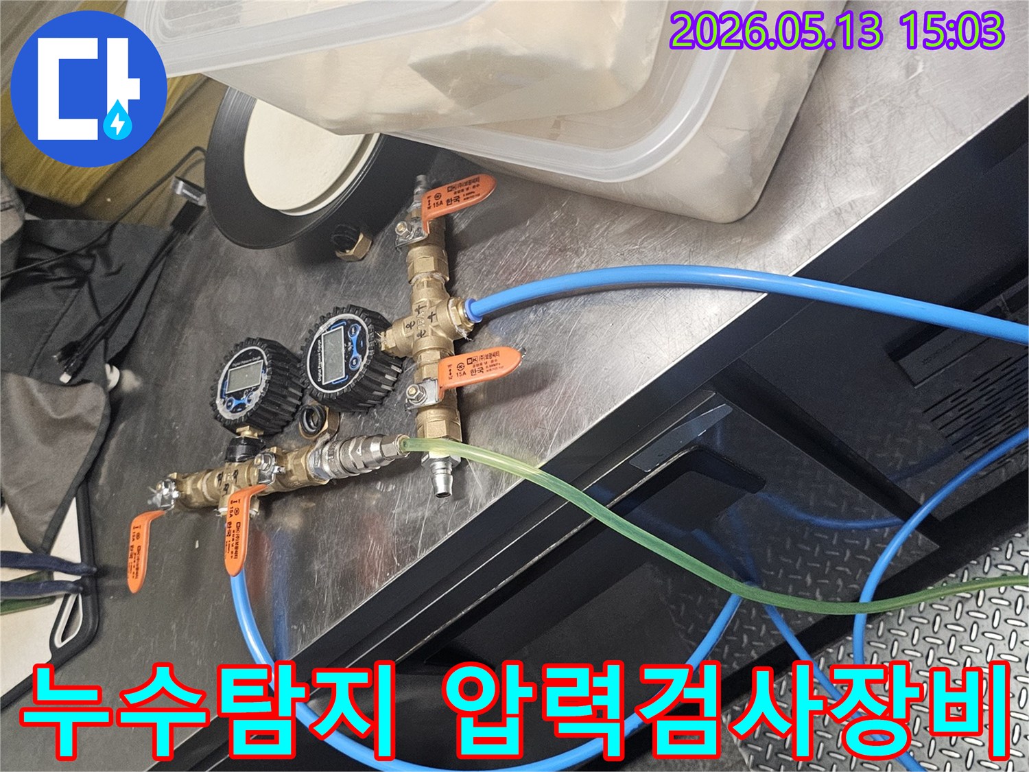 누수 탐지를 위해 배관에 연결된 압력 게이지와 밸브-그리고 호스들이 보이는 작업 현장 모습