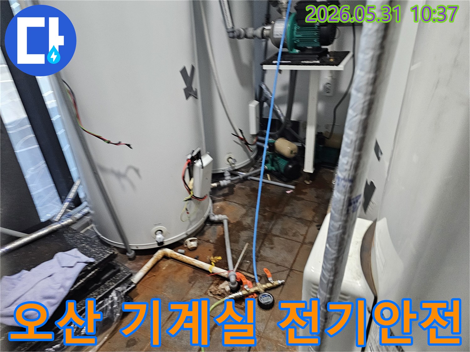 이 이미지는-오산-지역의-기계실에서-발생한-누수로-인한-전기-안전-위험을-전문가가-점검하고-해결하는-모습을-보여줍니다.