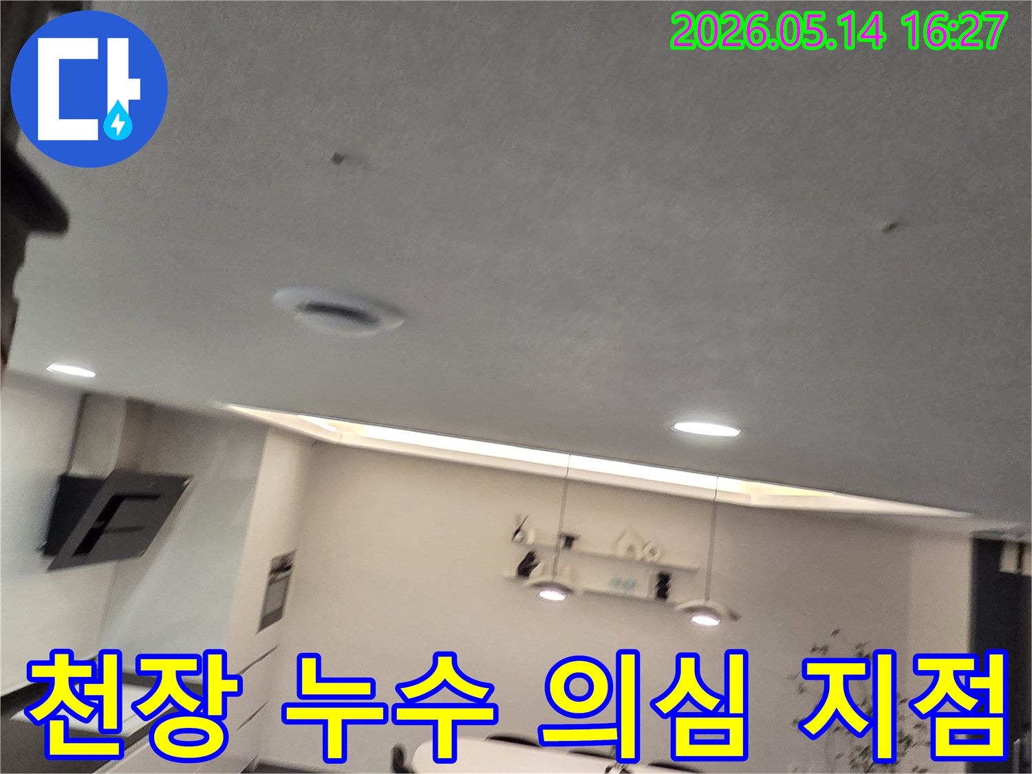 이 이미지는 현대적인 실내의-천장에 나타난-작은 물 얼룩과-환기구를 보여주며-윗층 누수나-배관 결함의-가능성을 시사합니다