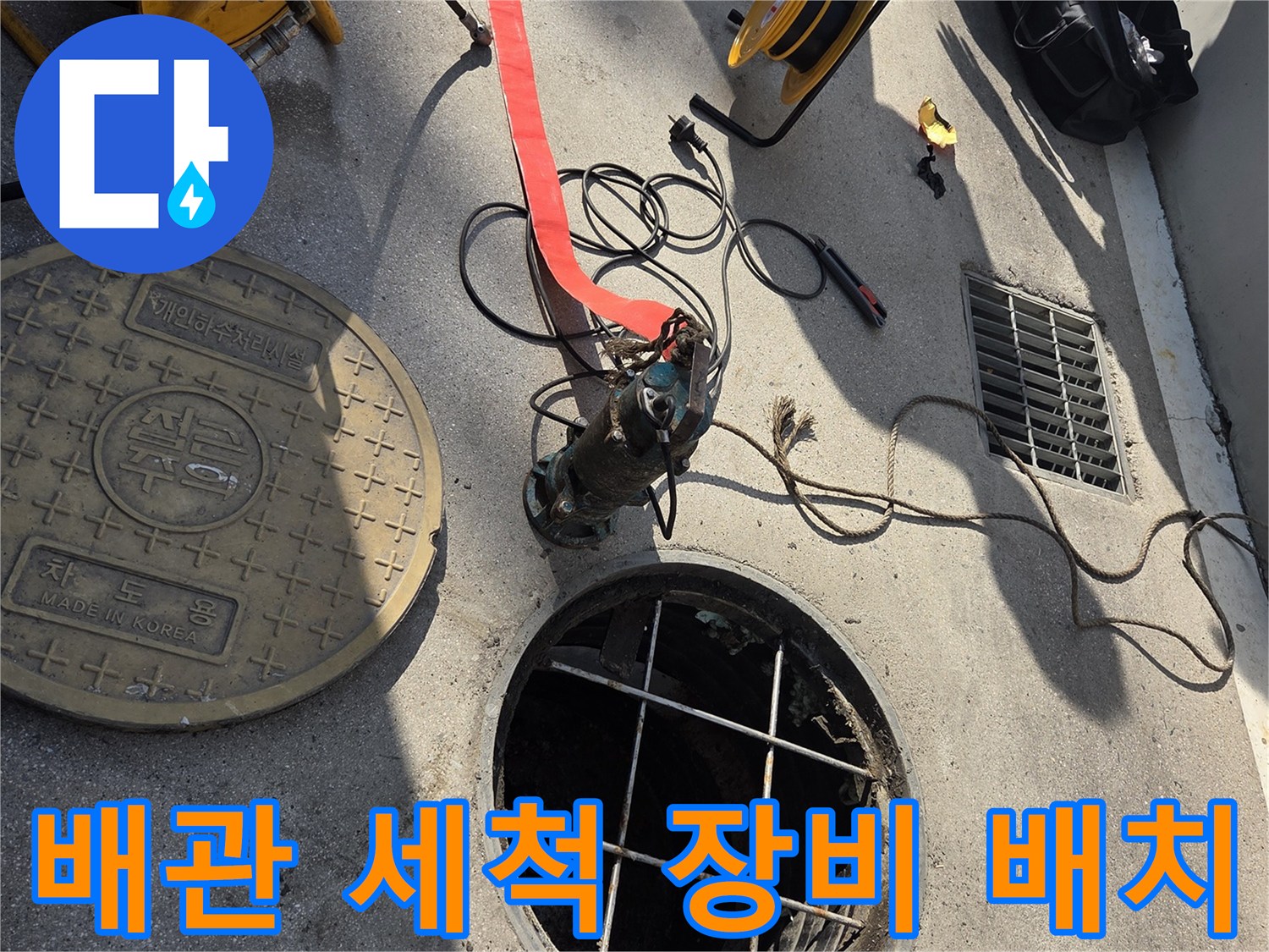 맨홀 입구 주변에 배치된 전문적인 배관 세척용 호스 릴입니다.