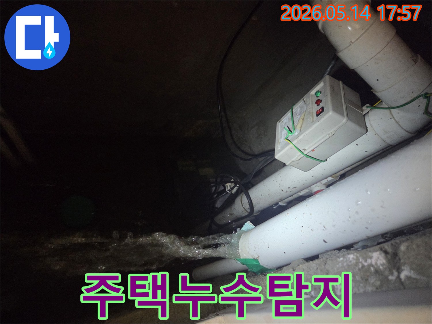 어두운 지하 공간에서-파이프에서 물이 세차게 뿜어져 나오는-주택 누수 현장을 보여주는 사진입니다-전기 제어 박스와 배관들이 함께 보입니다.