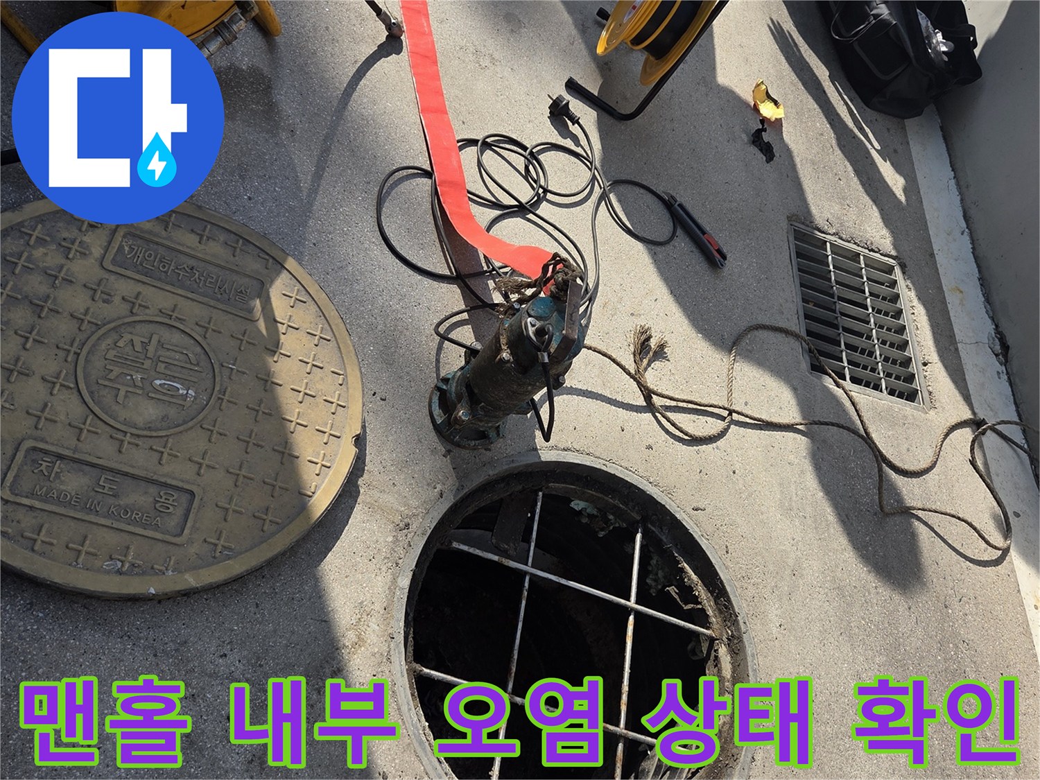 열린 맨홀과 배관 주변의 고압 세척용 릴 및 호스 연결 부위