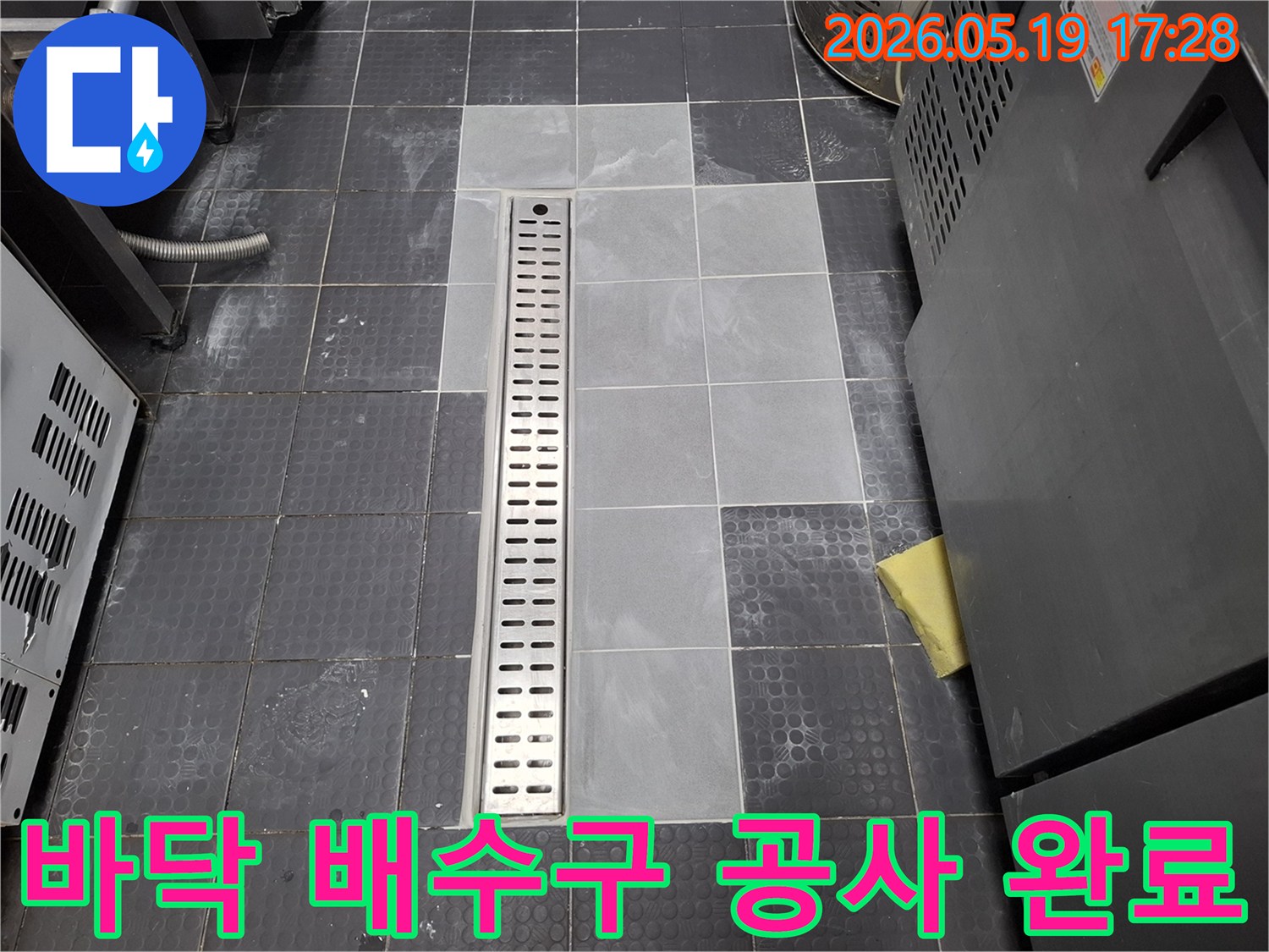 새롭게 설치된 스테인리스-스틸 바닥 배수구와 주변 타일 마감 모습